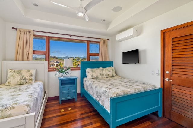 bedroom featuring an AC wall unit, ceiling fan, a raised ceiling, and dark hardwood / wood-style flooring