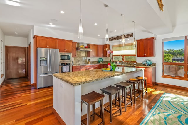 kitchen featuring wall chimney exhaust hood, sink, dark hardwood / wood-style flooring, and appliances with stainless steel finishes