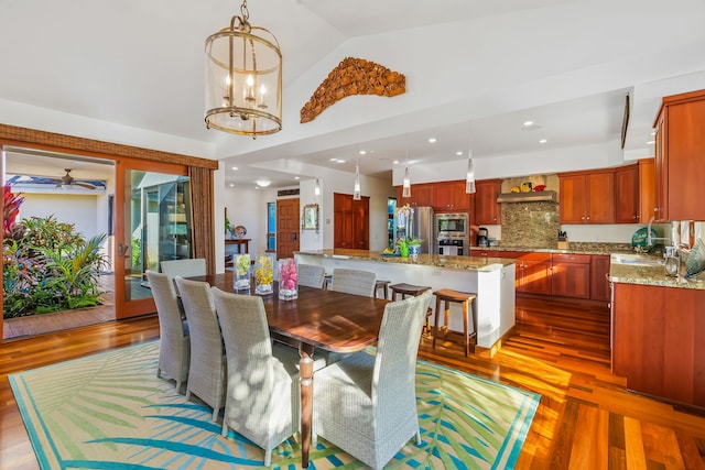 dining space featuring high vaulted ceiling, hardwood / wood-style floors, sink, and ceiling fan with notable chandelier