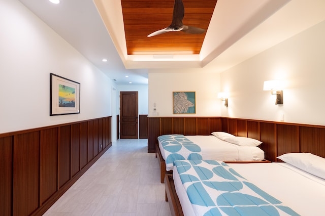 bedroom with a raised ceiling, ceiling fan, wooden walls, and wooden ceiling