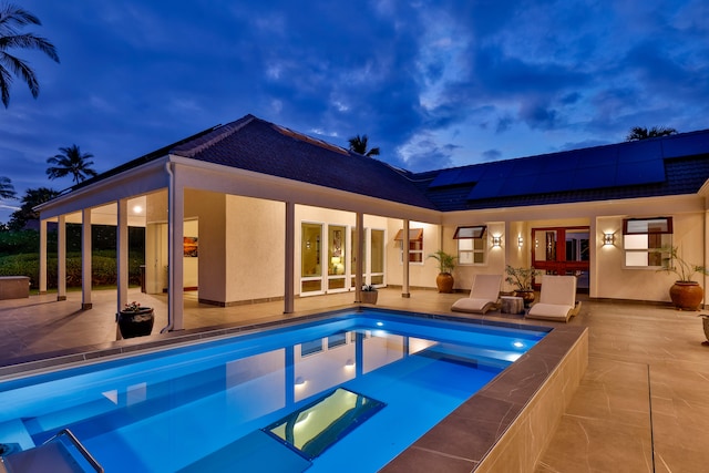 pool at dusk with a patio area