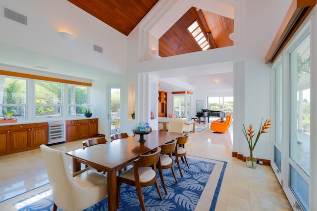 dining room featuring light tile patterned floors, high vaulted ceiling, beverage cooler, and wood ceiling