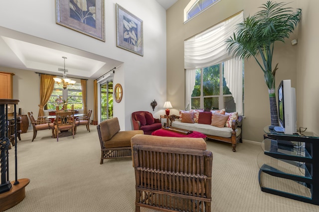 living room with carpet flooring, a raised ceiling, and a chandelier