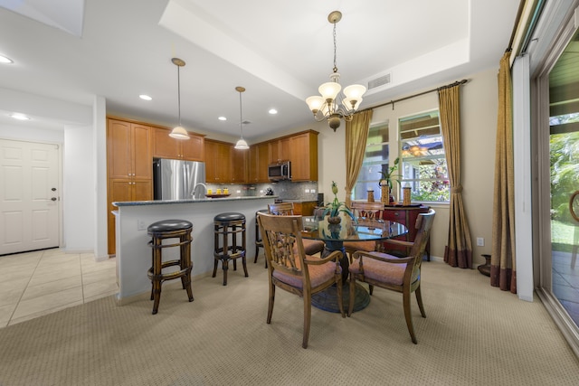 carpeted dining space featuring a tray ceiling and a chandelier