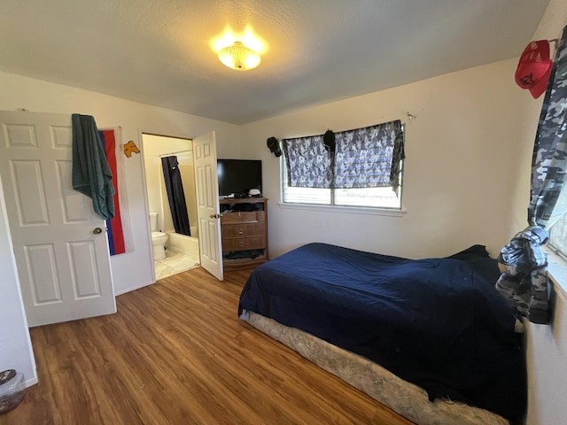 bedroom with wood-type flooring and connected bathroom