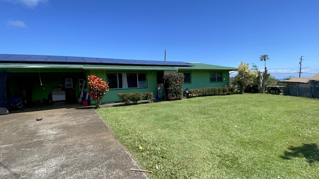 ranch-style home with solar panels, a front yard, and a carport