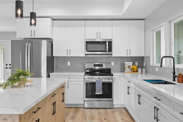 kitchen with light stone countertops, appliances with stainless steel finishes, sink, and white cabinets