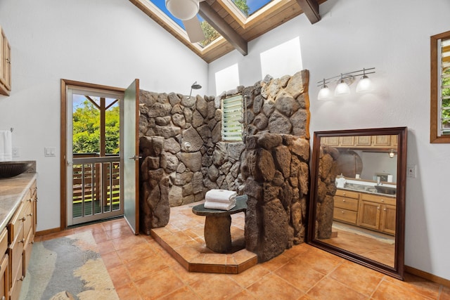 bathroom featuring beamed ceiling, vanity, tile patterned floors, and a skylight