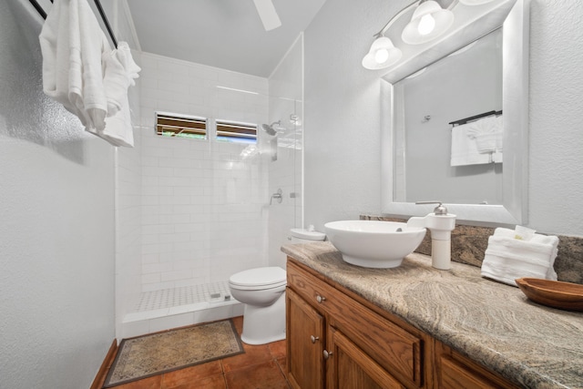 bathroom featuring tile patterned flooring, toilet, a tile shower, and vanity