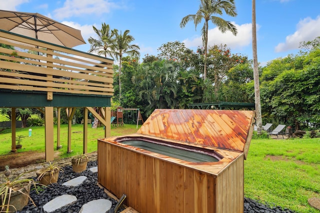 view of yard featuring a playground, a jacuzzi, and a deck