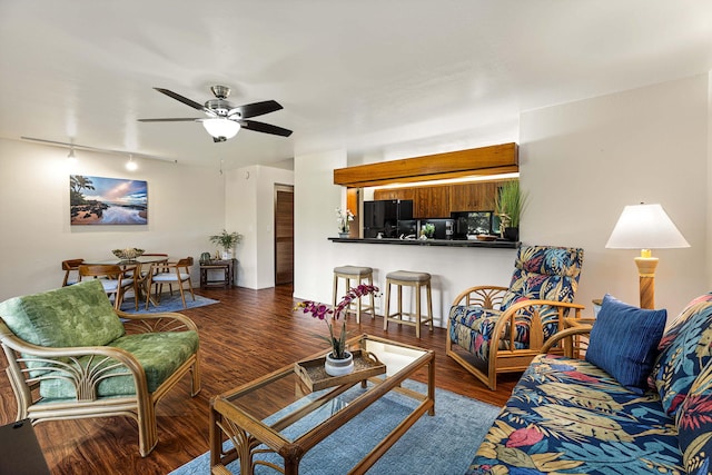 living room with ceiling fan, rail lighting, and dark wood-type flooring