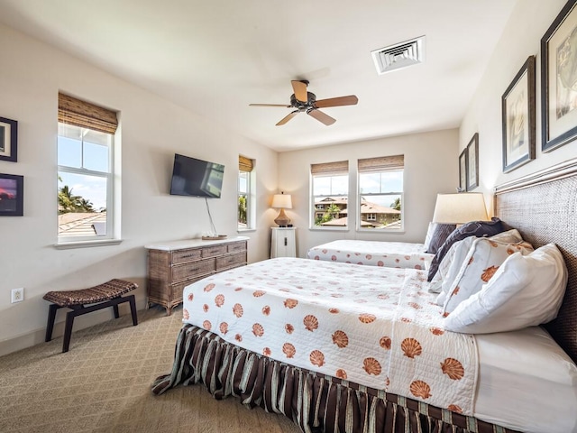 carpeted bedroom featuring multiple windows and ceiling fan