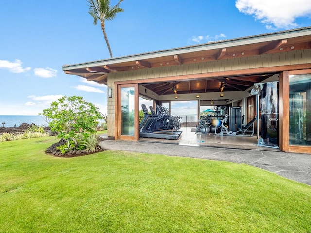 exterior space featuring a lawn, ceiling fan, and a water view