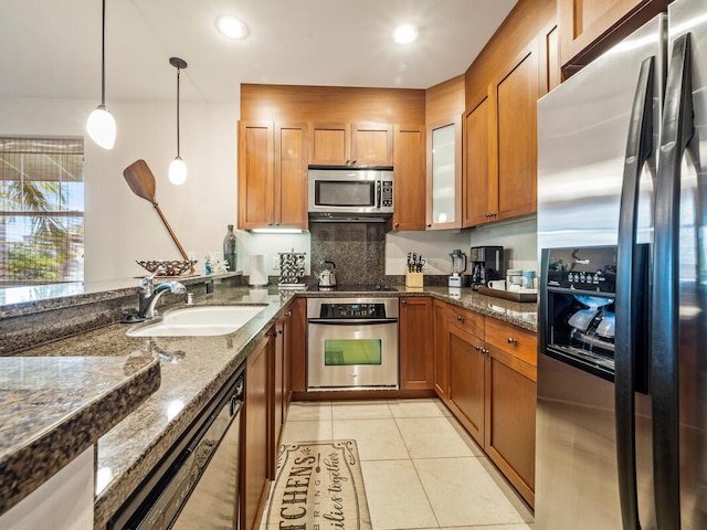 kitchen with sink, hanging light fixtures, dark stone countertops, light tile patterned flooring, and appliances with stainless steel finishes