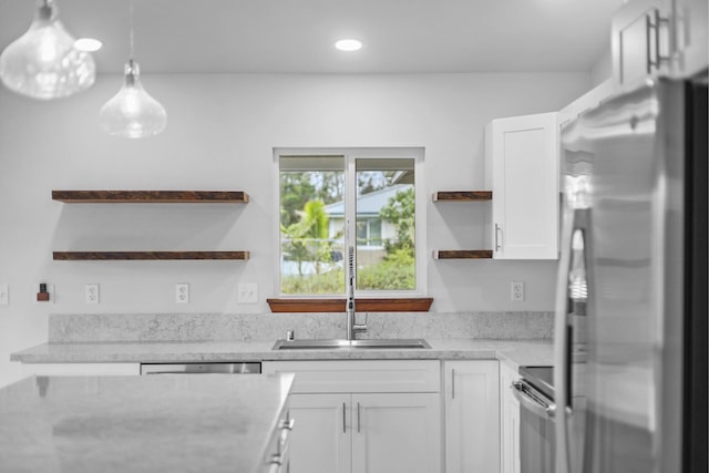 kitchen featuring appliances with stainless steel finishes, decorative light fixtures, white cabinetry, and sink