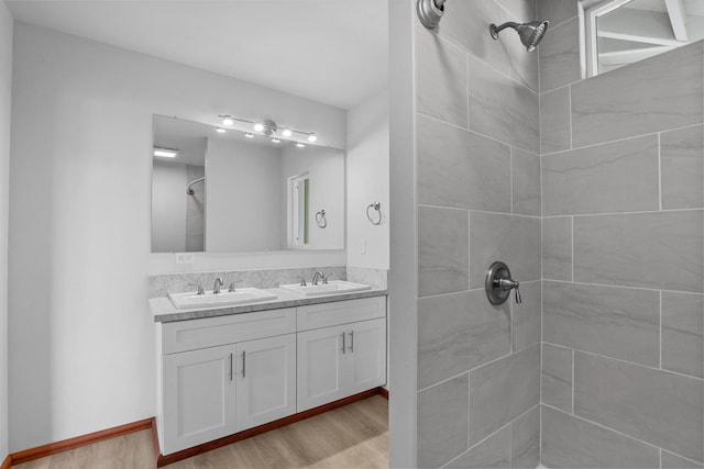 bathroom with hardwood / wood-style floors, vanity, and a tile shower