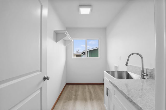 laundry area with washer hookup, sink, cabinets, and light hardwood / wood-style floors