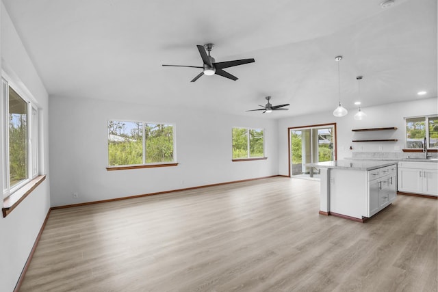 kitchen with sink, ceiling fan, light wood-type flooring, decorative light fixtures, and white cabinetry