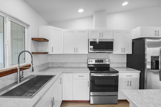 kitchen with white cabinets, appliances with stainless steel finishes, vaulted ceiling, and sink