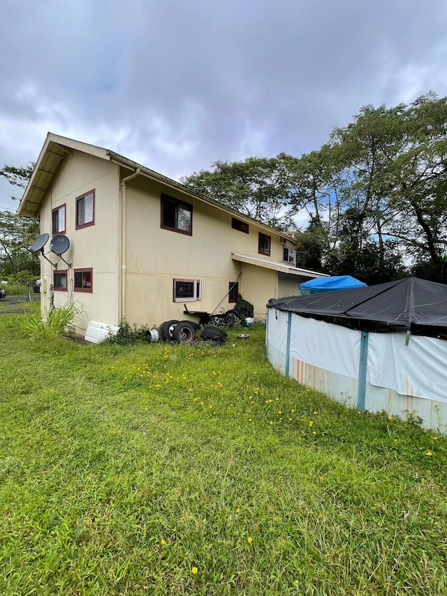 back of property featuring a yard and a covered pool