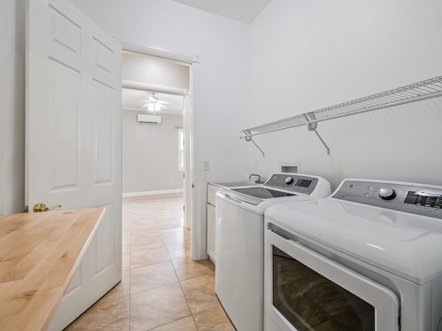 clothes washing area featuring cabinets, a wall unit AC, washing machine and clothes dryer, light tile flooring, and ceiling fan