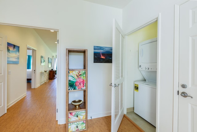 laundry room featuring light wood-type flooring and stacked washer / dryer