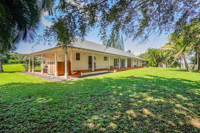 rear view of property with a lawn and a shed