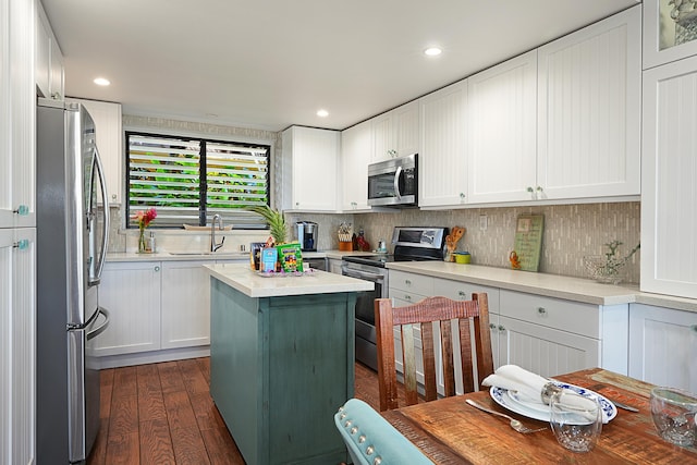 kitchen with dark wood-type flooring, a kitchen island, white cabinetry, appliances with stainless steel finishes, and sink