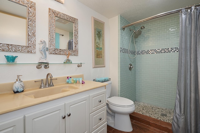 bathroom with hardwood / wood-style floors, toilet, walk in shower, vanity, and a textured ceiling