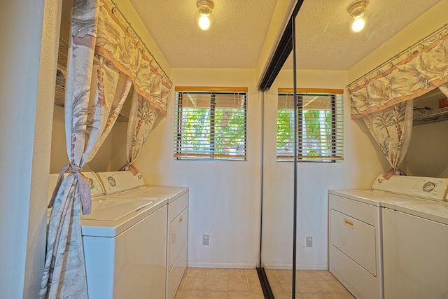 laundry room featuring washing machine and clothes dryer, light tile patterned floors, and a textured ceiling