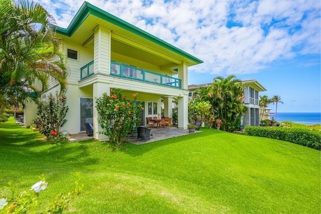 back of property with a patio, a water view, a yard, and a balcony