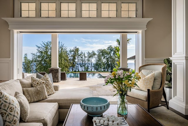 living room featuring a wainscoted wall, decorative columns, and a decorative wall