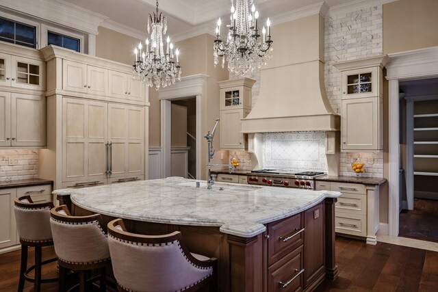 kitchen with backsplash, a notable chandelier, dark hardwood / wood-style flooring, and an island with sink