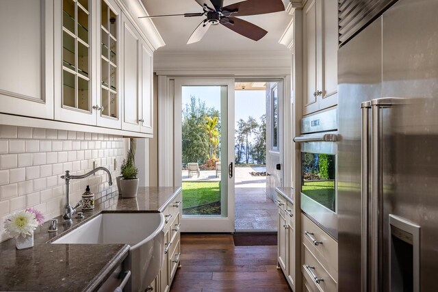 kitchen with dark stone counters, backsplash, ceiling fan, dark hardwood / wood-style floors, and appliances with stainless steel finishes