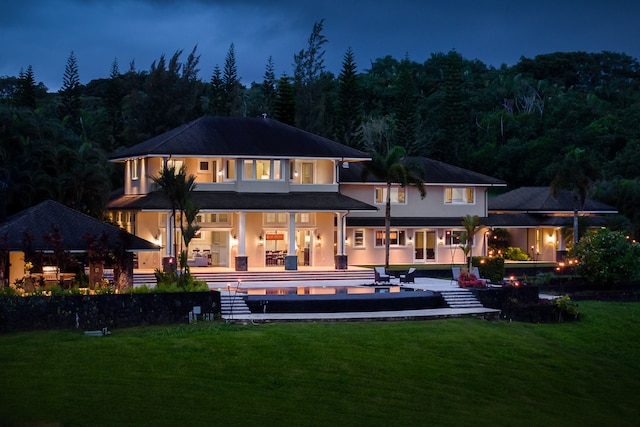 back house at twilight featuring a lawn