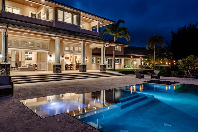 pool at night with a patio area, an outdoor living space, and an outdoor pool