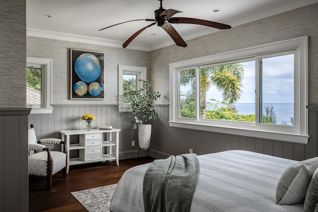 bedroom featuring a wainscoted wall, ceiling fan, ornamental molding, dark wood-style flooring, and a water view