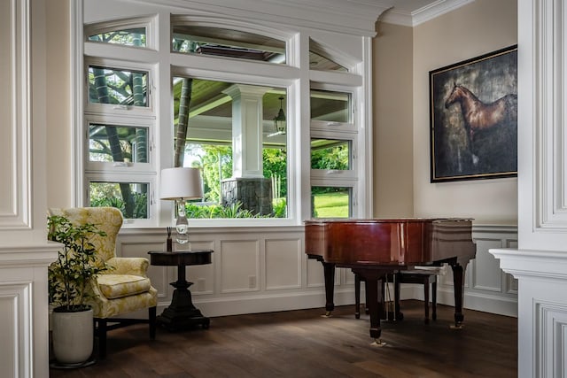 sitting room featuring dark wood-style floors, a decorative wall, crown molding, and ornate columns