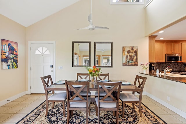 tiled dining room with high vaulted ceiling, ceiling fan, and sink