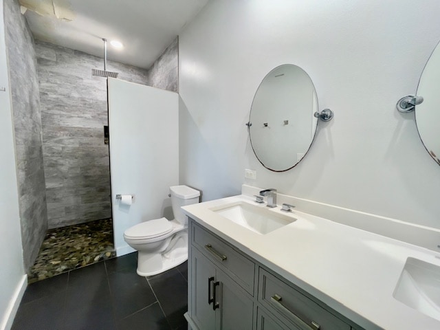 bathroom featuring tile patterned flooring, a tile shower, vanity, and toilet