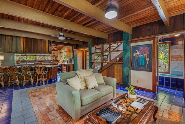 tiled living room with beam ceiling, ceiling fan, wooden walls, and wood ceiling