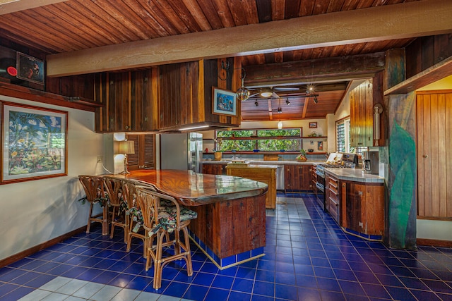 kitchen featuring dark tile patterned floors, kitchen peninsula, stainless steel appliances, and wooden ceiling