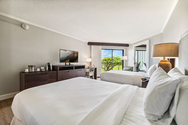 bedroom featuring access to exterior, hardwood / wood-style flooring, a textured ceiling, and ornamental molding