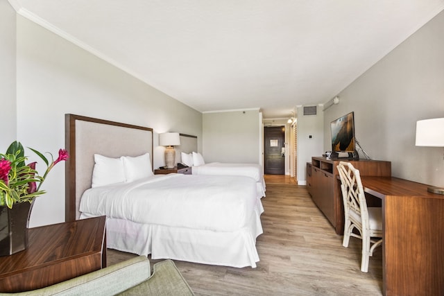 bedroom with light hardwood / wood-style floors and crown molding