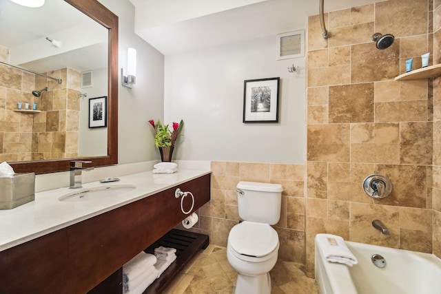 full bathroom featuring toilet, tile walls, tiled shower / bath, tile patterned floors, and vanity