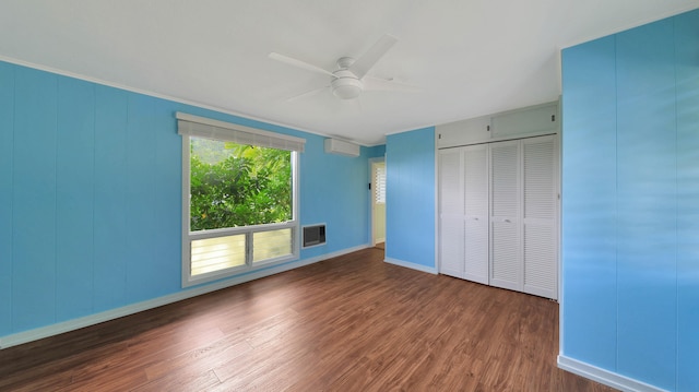 unfurnished bedroom with a wall unit AC, dark hardwood / wood-style flooring, ceiling fan, and a closet