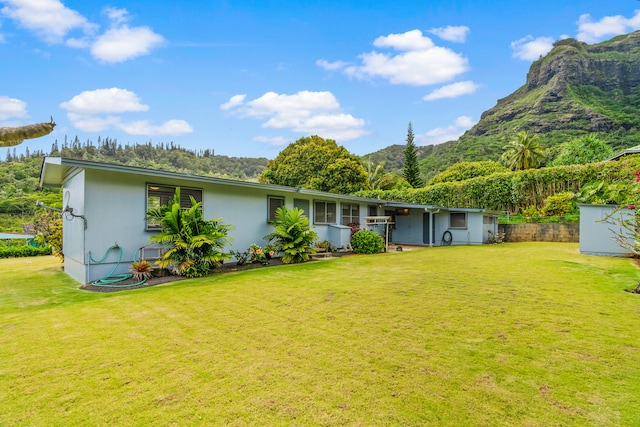 back of property with a mountain view and a yard