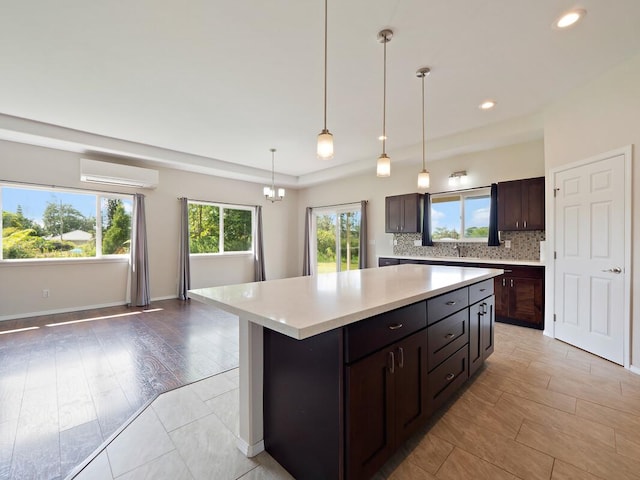 kitchen with backsplash, a wall mounted air conditioner, hanging light fixtures, dark brown cabinetry, and a center island