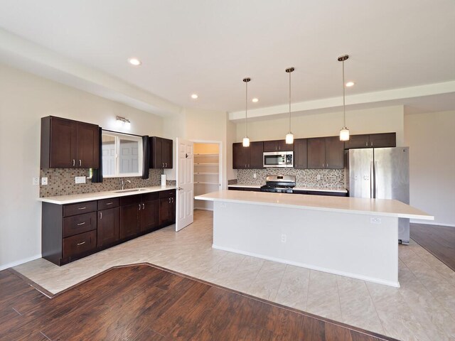 kitchen featuring sink, hanging light fixtures, stainless steel appliances, and a kitchen island