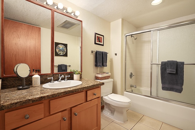 full bathroom featuring toilet, vanity, tile patterned floors, bath / shower combo with glass door, and a textured ceiling